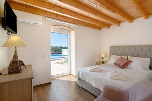 Une chambre avec un lit, des tables de chevet, une lampe et une vue sur une piscine extérieure.