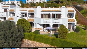 A white building with multiple balconies, a patio area with outdoor furniture, and a stone pathway leading to the entrance. - Holiday Apartment in Albufeira Resort with Check-in, Terrace, and Pools (Albufeira)