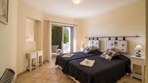 A bedroom with two beds, a small desk, a chair, a nightstand, and a window with curtains. - Holiday Apartment in Albufeira Resort with Check-in, Terrace, and Pools (Albufeira)