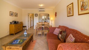 A living room with a sofa, a coffee table, a dining table with chairs, and a cabinet. - Holiday Apartment in Albufeira Resort with Check-in, Terrace, and Pools (Albufeira)
