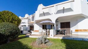 A white building with a patio area, outdoor seating, and a well-maintained lawn. - Holiday Apartment in Albufeira Resort with Check-in, Terrace, and Pools (Albufeira)