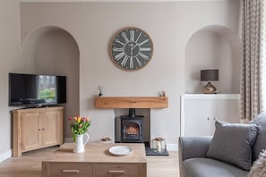 Un salon avec une télévision, une cheminée, une horloge et un canapé.