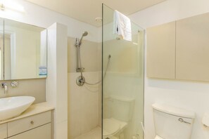 A bathroom with a glass-enclosed shower, a white sink, and a toilet.