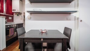 Una cocina compacta con una mesa de comedor, sillas y un farol rojo.