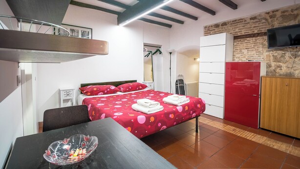 Un dormitorio con cama, escritorio, silla, armario y televisor.