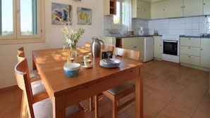A spacious kitchen with a dining area, featuring a wooden table, chairs, and a coffee maker. - Alonissos 4-bedroom Large Villa With Private Pool (Alonissos)