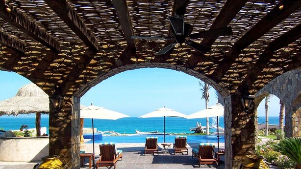A covered outdoor seating area with a view of the ocean, stone pillars, and umbrellas. - Relax by Your Private Pool, San Jose Del Cabo 1041 (San Jose Del Cabo)