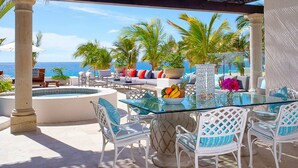 Un espace extérieur aménagé avec une table en verre, des chaises blanches et une piscine.