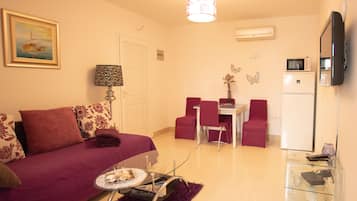Cozy living space with a sofa, dining area, flat-screen TV, and modern decor.