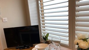 Een eettafel met borden, een wijnglas en een afstandsbediening.