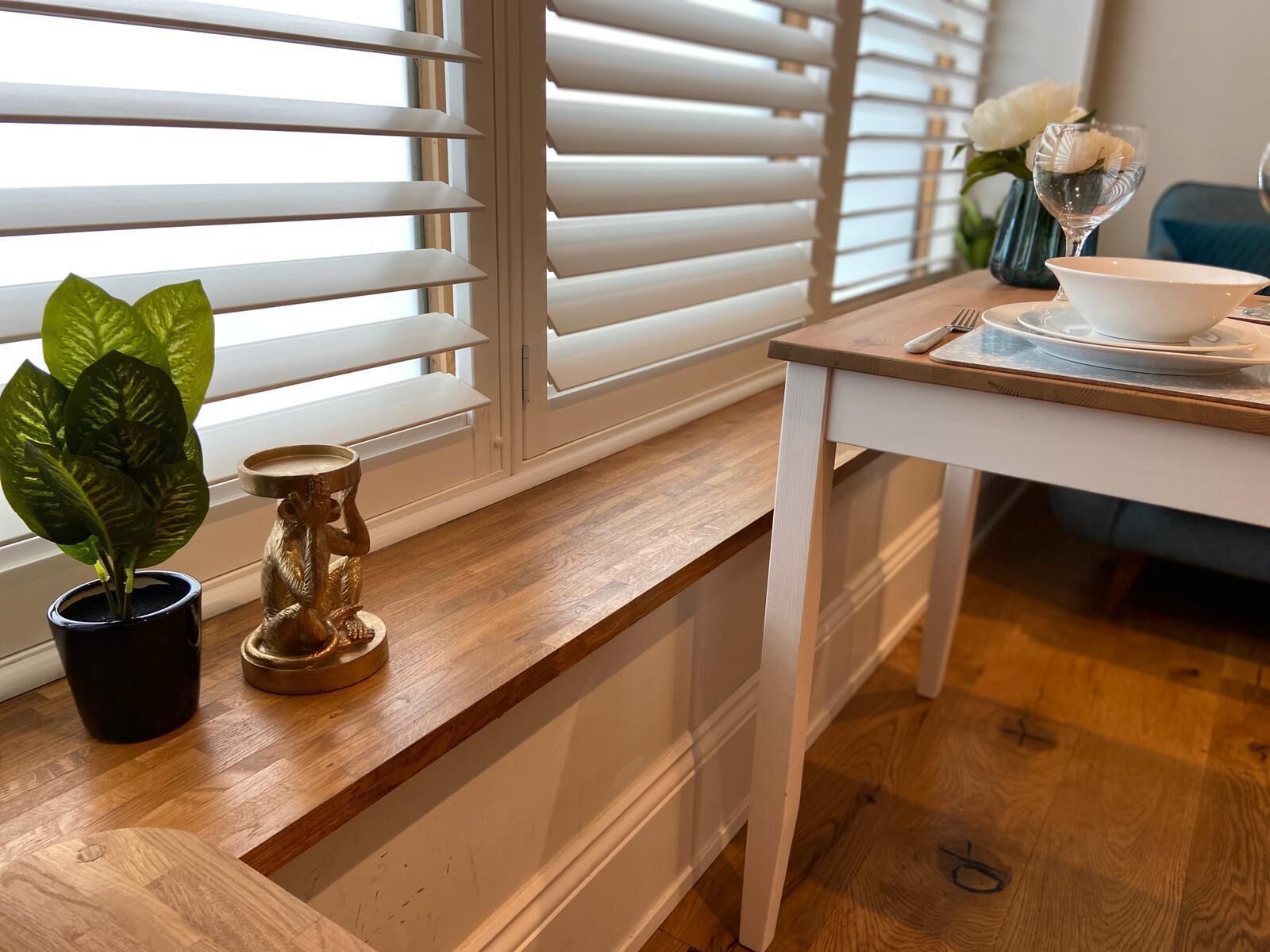 Een houten bankje met een bloempot en een decoratief object.