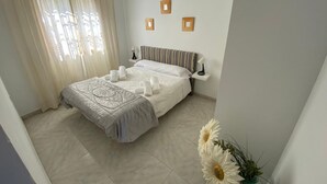 Une chambre à coucher bien rangée, avec un lit, des tables de chevet et une fenêtre avec des rideaux.