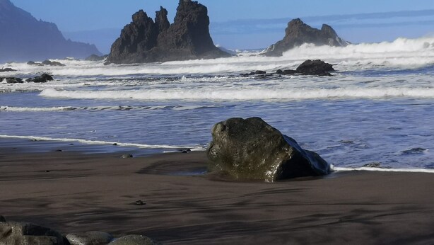 Une plage avec de gros rochers et des vagues.
