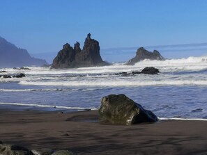Ein Strand mit großen Felsen und Wellen.