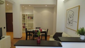 A modern living room with a dining area, a bookshelf, and a framed artwork on the wall. - PortonHouse (Roma)