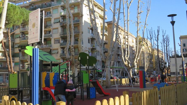 A playground with play structures, surrounded by a wooden fence and trees. - PortonHouse (Roma)