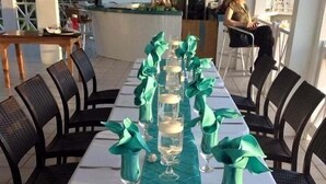 Een lange eettafel met smaragdgroene servetten en champagneglazen, omringd door zwarte stoelen.