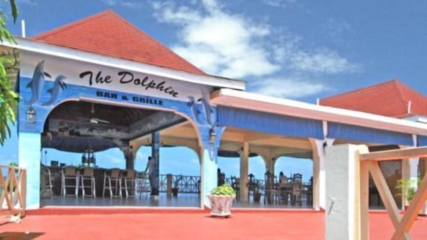 Een gebouw met een rood dak en een bord waarop staat 'The Dolphin Bar & Grill'.
