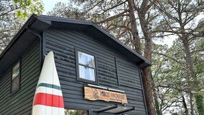 Un pequeño edificio de madera oscura con un letrero que dice 'Mike House'.