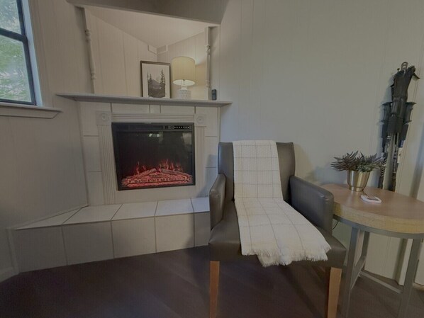 A living room with a fireplace, a sofa, a table with a lamp, and a potted plant.