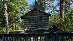 Ein Whirlpoolbereich mit einer Holzhütte im Hintergrund, auf der Beschilderung steht 'Pine Lodge'.