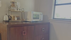 Eine Küche mit Mikrowelle, Wasserkocher und Kaffeemaschine auf einem Holzschrank.