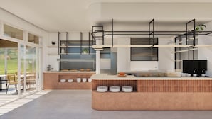 A modern kitchen with a central island, built-in shelves, and a dining area with chairs. - Kalloudis Apartment (Kos)