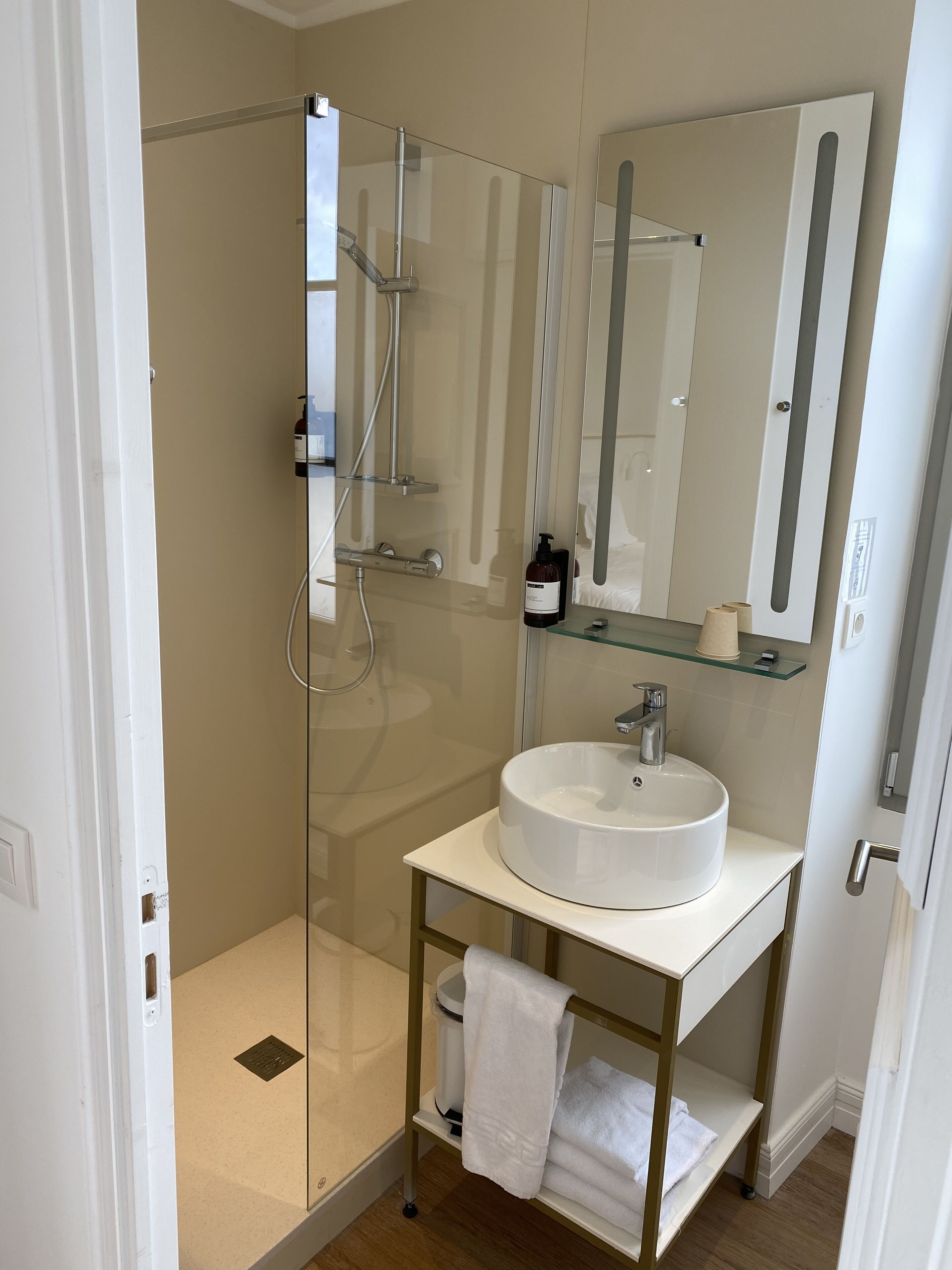 A modern bathroom with a glass-enclosed shower, a white sink, and a mirror above it.