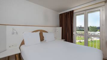 Una habitación de hotel con una cama grande, un escritorio y una ventana con cortinas.
