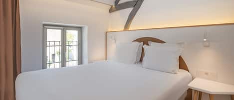 Un dormitorio con una cama grande, una ventana y una mesita de noche.