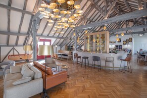 A spacious loft-style interior with a high ceiling, exposed wooden beams, a central bar area, and a mix of seating options including a sofa and chairs. - La Clef des Chateaux (Maslives)