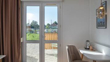 Une chambre avec un lit, une chaise, une petite table, une machine à café et une vue sur l’extérieur.