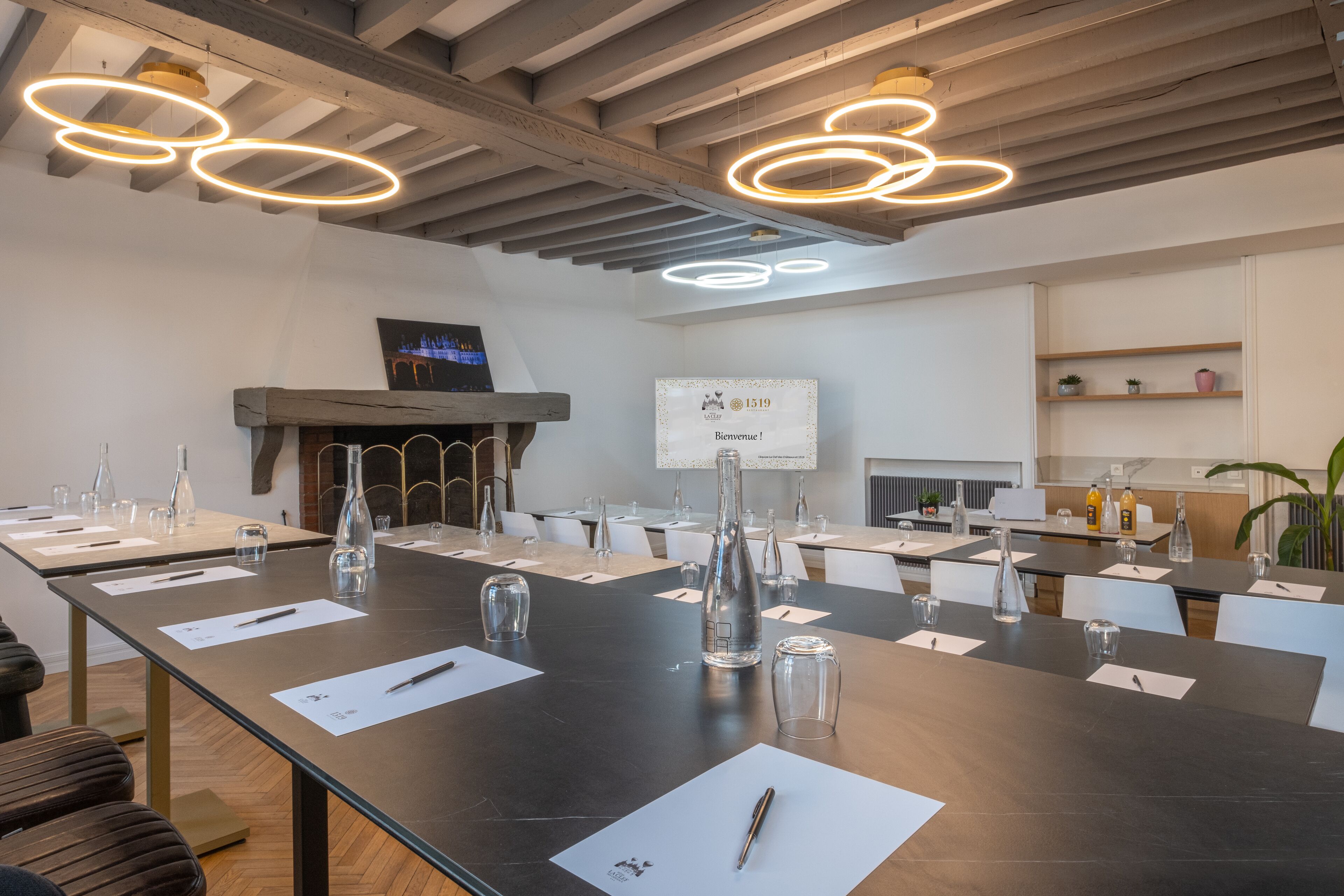 A modern conference room with a long table, chairs, and a fireplace.