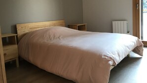 Un dormitorio con estructura de cama de madera, una mesita de noche y un radiador.
