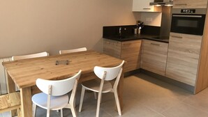 Una cocina moderna con una mesa de madera y sillas blancas, encimera negra y armarios empotrados.