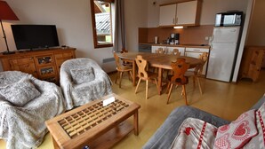 Un espacio habitable compacto con comedor, kitchenette y televisor.