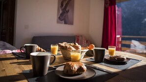 Un desayuno con cruasanes, jugo y café sobre una mesa de madera en una habitación con vistas.