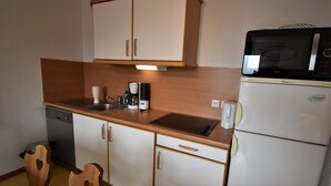 Una kitchenette compacta con microondas, cafetera y un refrigerador pequeño.