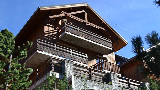 Un edificio de madera de varios pisos con balcones y un puente de piedra.