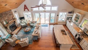 A spacious living area with a fireplace, comfortable seating, and a large window overlooking a deck. - Just Bluffin': Keuka Lake Luxury Rental + Hot Tub! Close to Wineries (Penn Yan)
