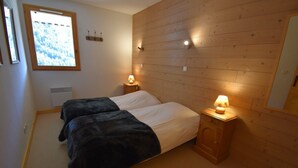 Una habitación con dos camas, paredes de madera, una ventana con vistas y lámparas de noche.