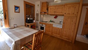 Una cocina con armarios de madera, una mesa de comedor con mantel a cuadros y una silla de madera.