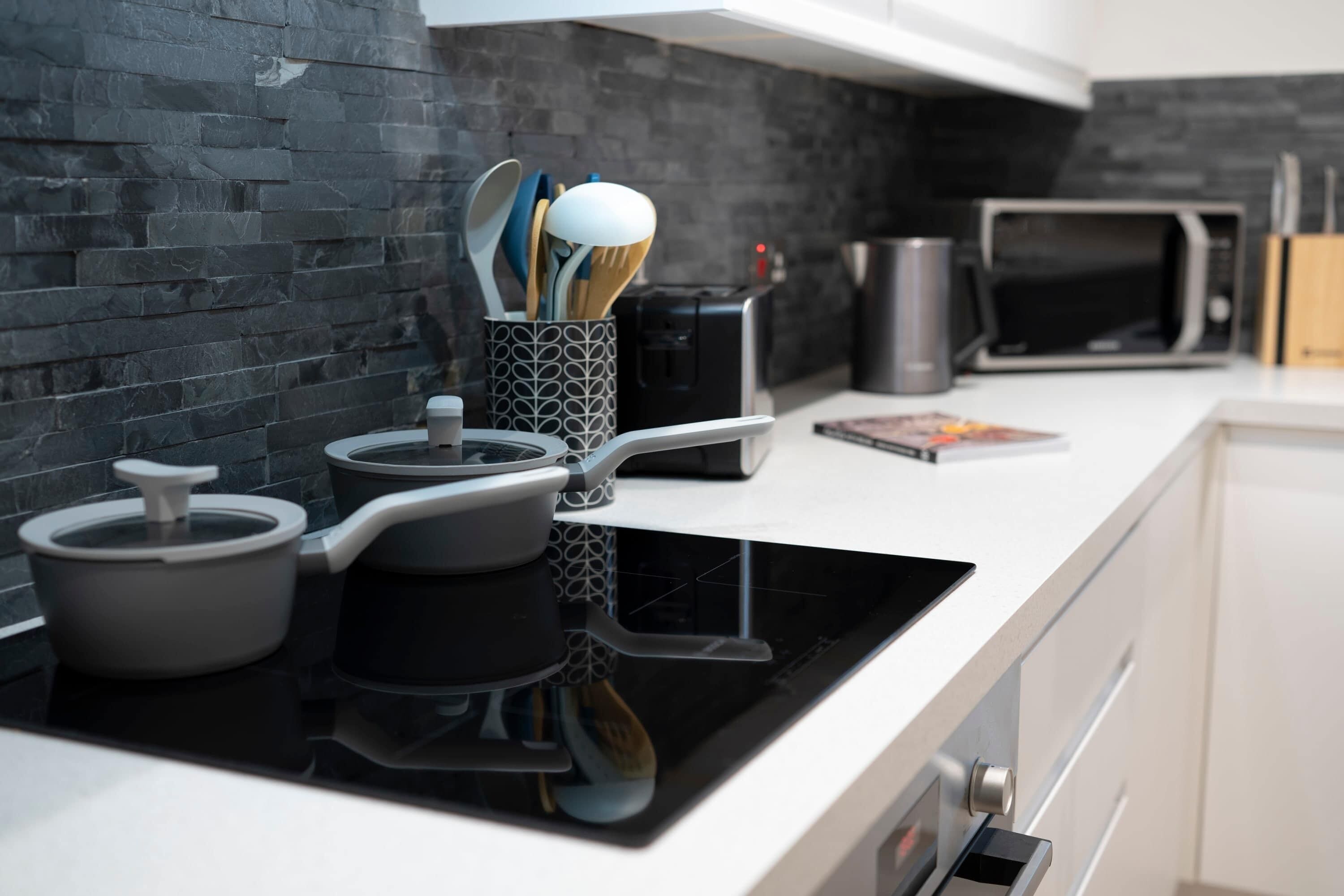 A modern kitchen with a black stovetop, a microwave, and a coffee maker.