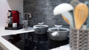 Eine moderne Küche mit schwarzem Arbeitsplatz, einer roten Krups-Kaffeemaschine und grauen Kochtöpfen.