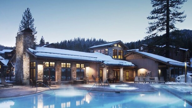 A lodge with a pool, stone exterior, and large windows.