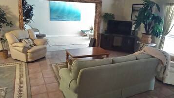 Un salon comprenant un canapé, un fauteuil, une table basse et un meuble pour la télévision.