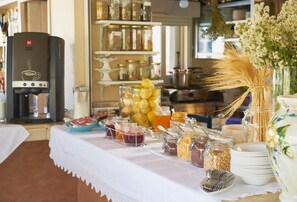 Une table de buffet garnie de divers plats, une machine à café et des éléments décoratifs tels que des fleurs et des vases.