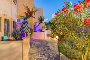 A stone-paved pathway leading to a building with a reception area, outdoor seating, and a garden with flowering plants. - Golden Bay Apartments-garden Haven (Hersonissos)