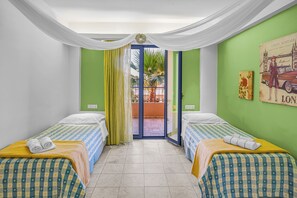 Ett hotellrum med två sängar, utsikt över omgivningarna och en dörr som leder ut till en balkong.