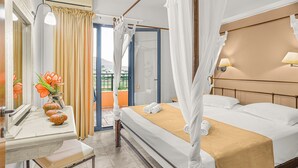 A hotel room with a bed, a bedside table, a mirror, a window with curtains, and a view of the outdoors. - Golden Bay Apartments-garden Haven (Hersonissos)